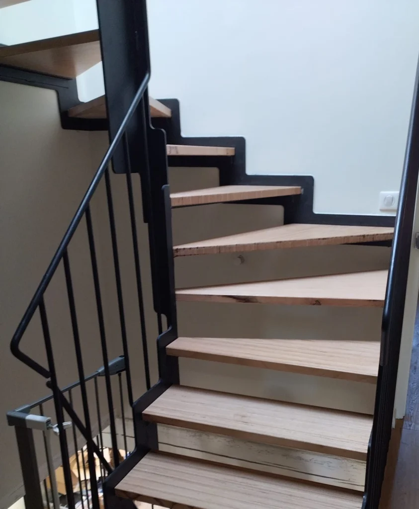 Escalier quart tournant, limons crémaillère en acier noir, marches en bois et rampe à barreaux