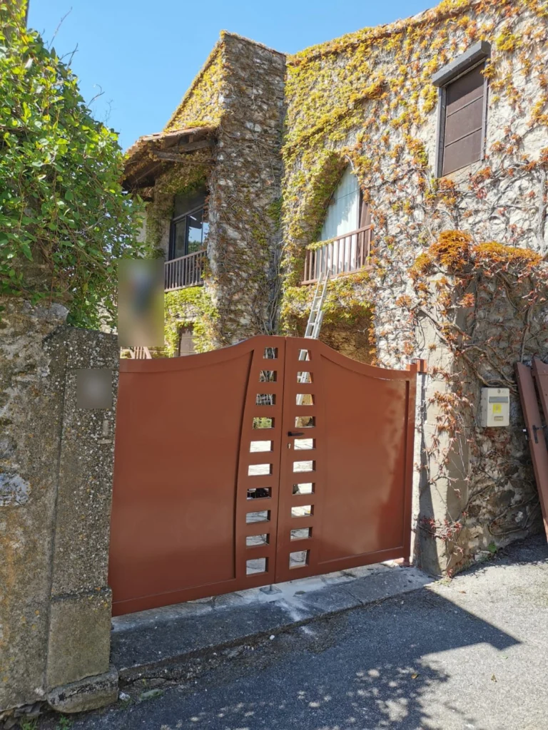 Portail battant cintré couleur terre cuite devant une maison en pierre, posé par Pro Menuiserie Soudure, ferronnier à Montpellier