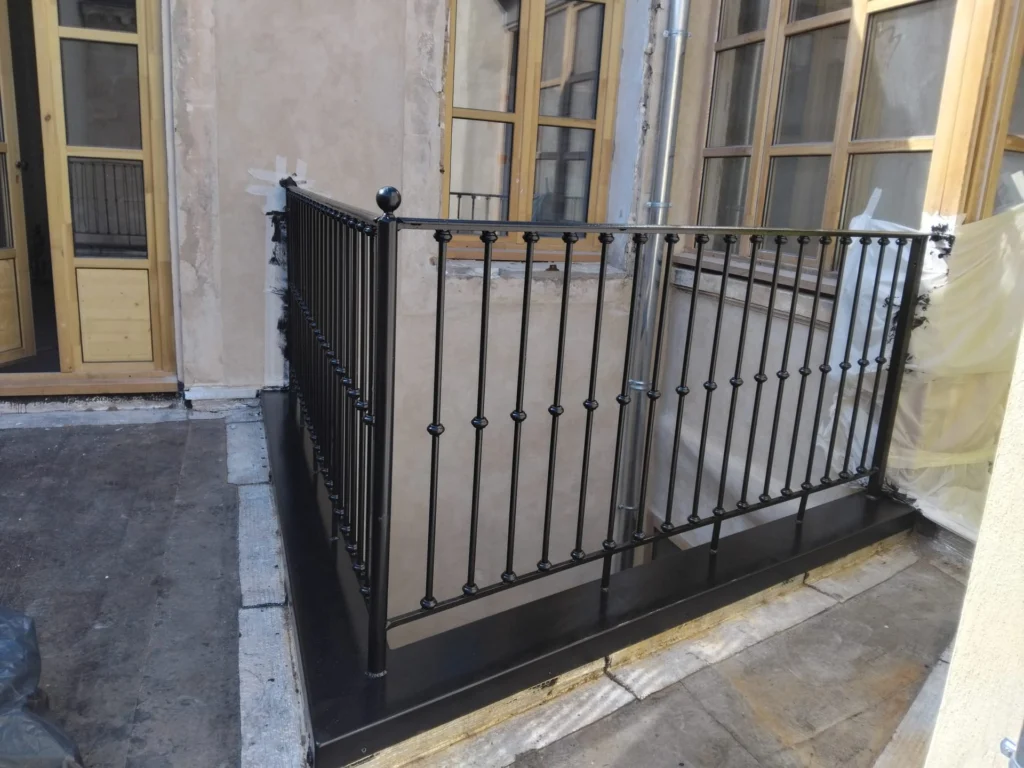 Garde-corps sur mesure en acier noir à barreaux ornés de bagues et pommeaux, autour d’une terrasse