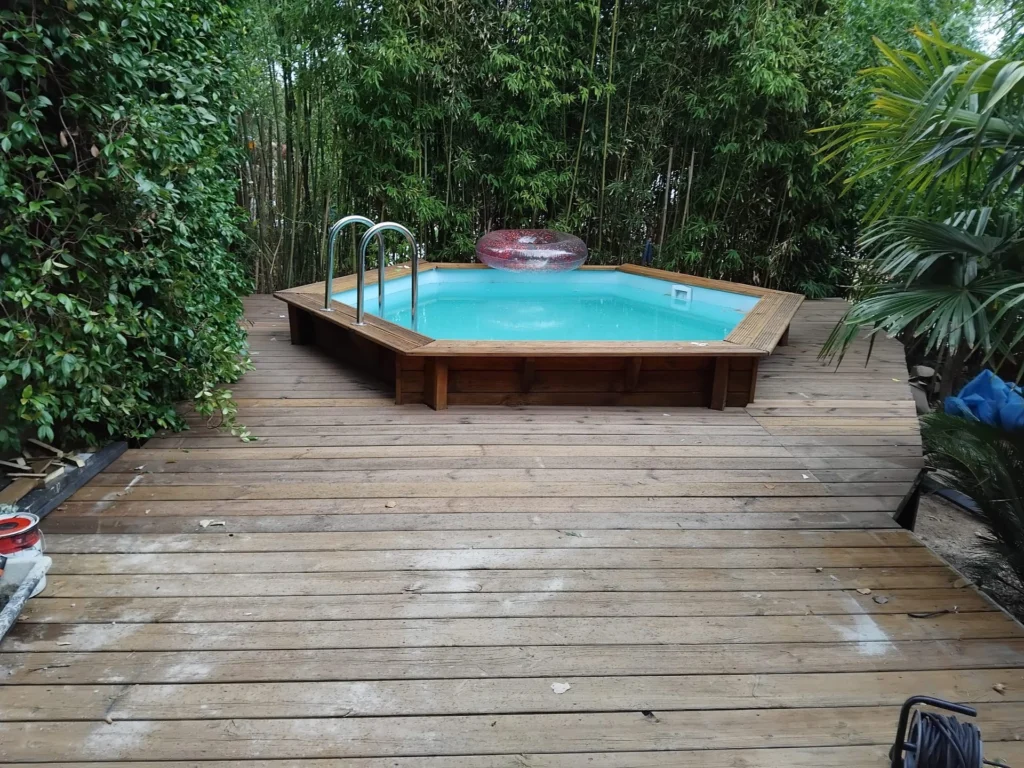 Terrasse en bois terminée autour d’une piscine hors-sol, dans un jardin